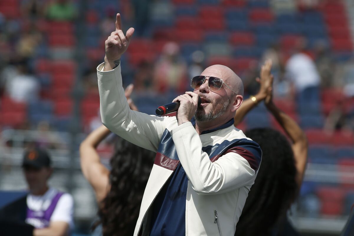 Pitbull holds a microphone at a NASCAR venue.