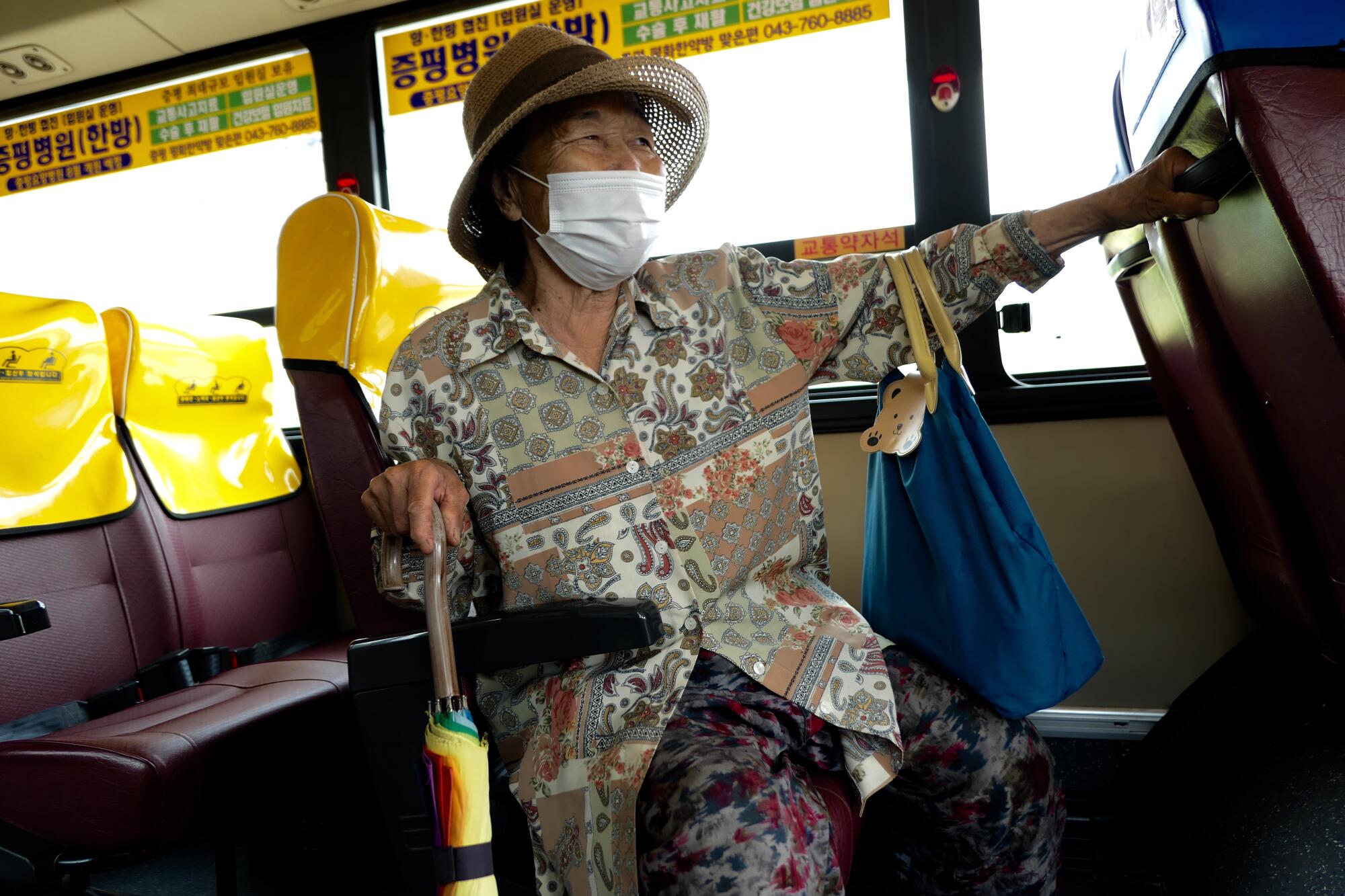 A woman holds on to an umbrella handle while sitting on the bus