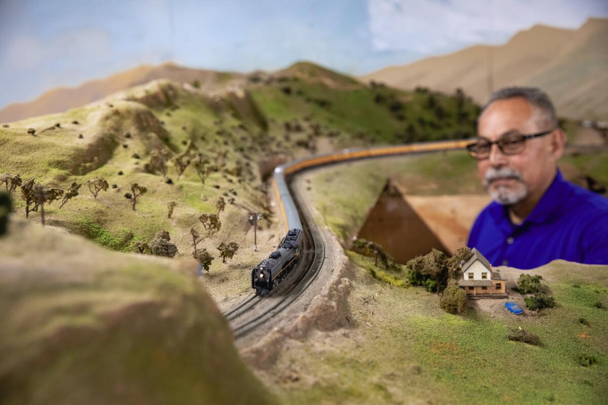 A man emerges from a trap door in a railroad track layout.