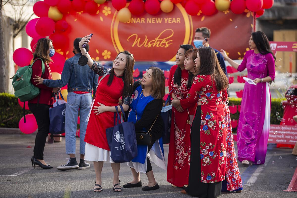 Women dressed in "Ao Dai" Vietnamese traditional attire take a selfie during the Lunar New Year celebration.