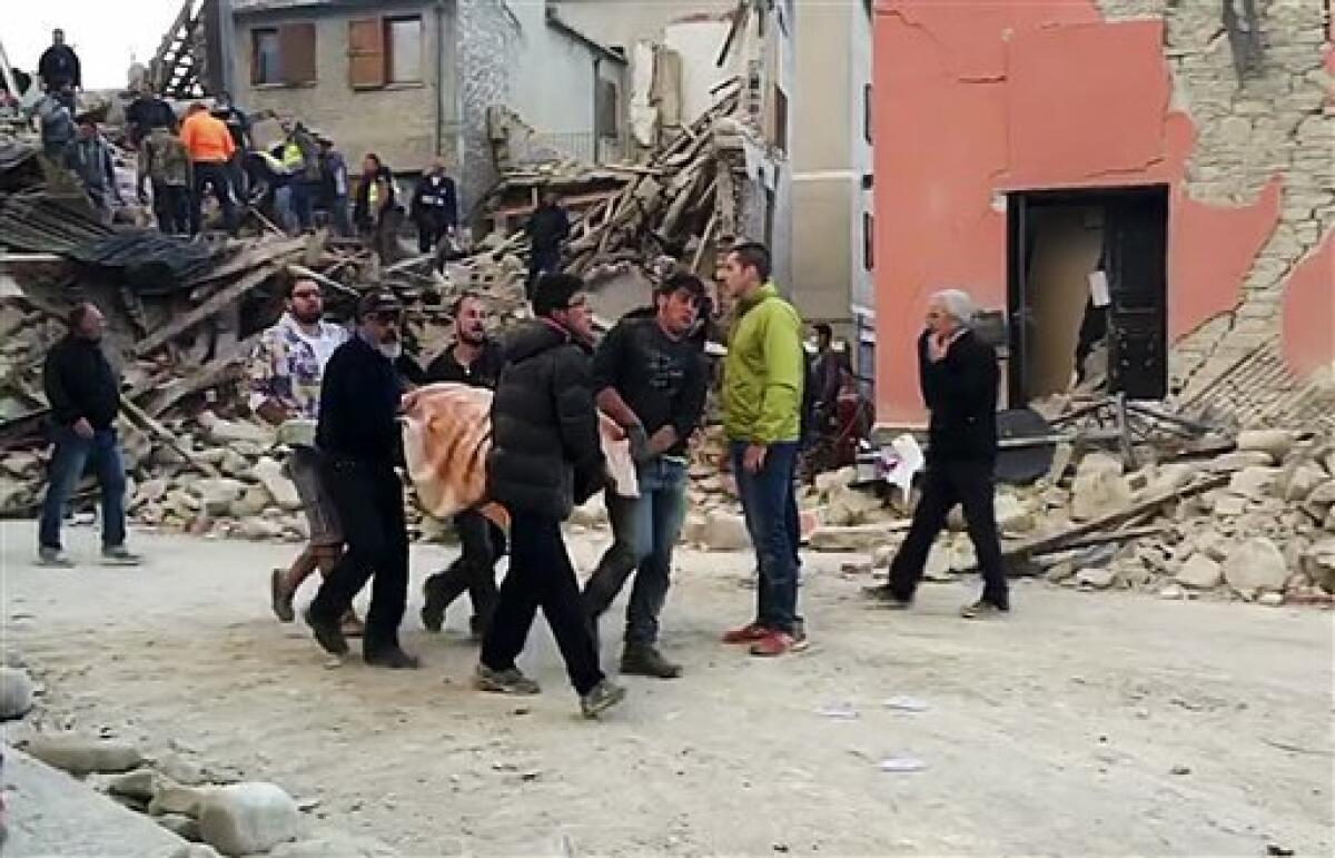 En esta imagen, tomada de un video, personas recuperan a una víctima de debajo de los escombros de un edificio en Amatrice, una localidad del centro de Italia sacudida por un sismo de magnitud 6,1,.