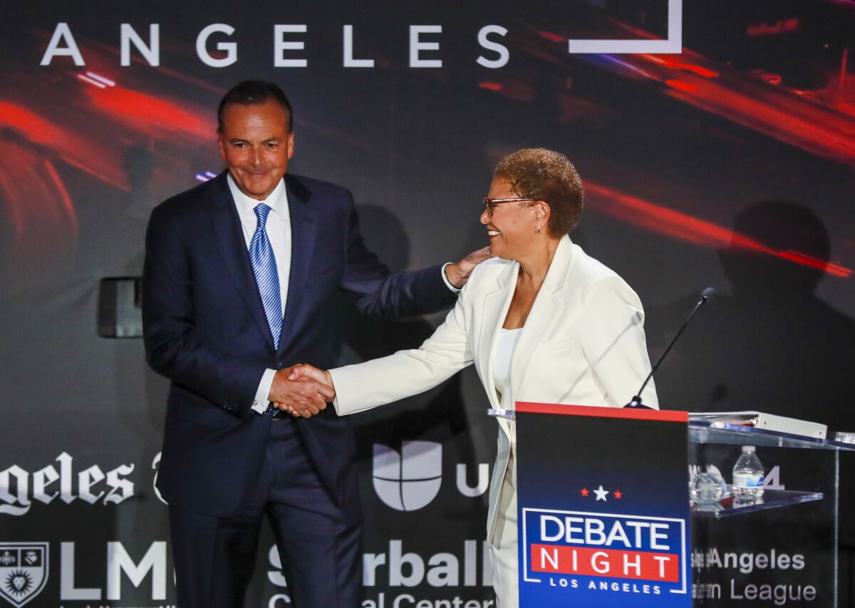 Rick Caruso and Karen Bass shaking hands on a stage