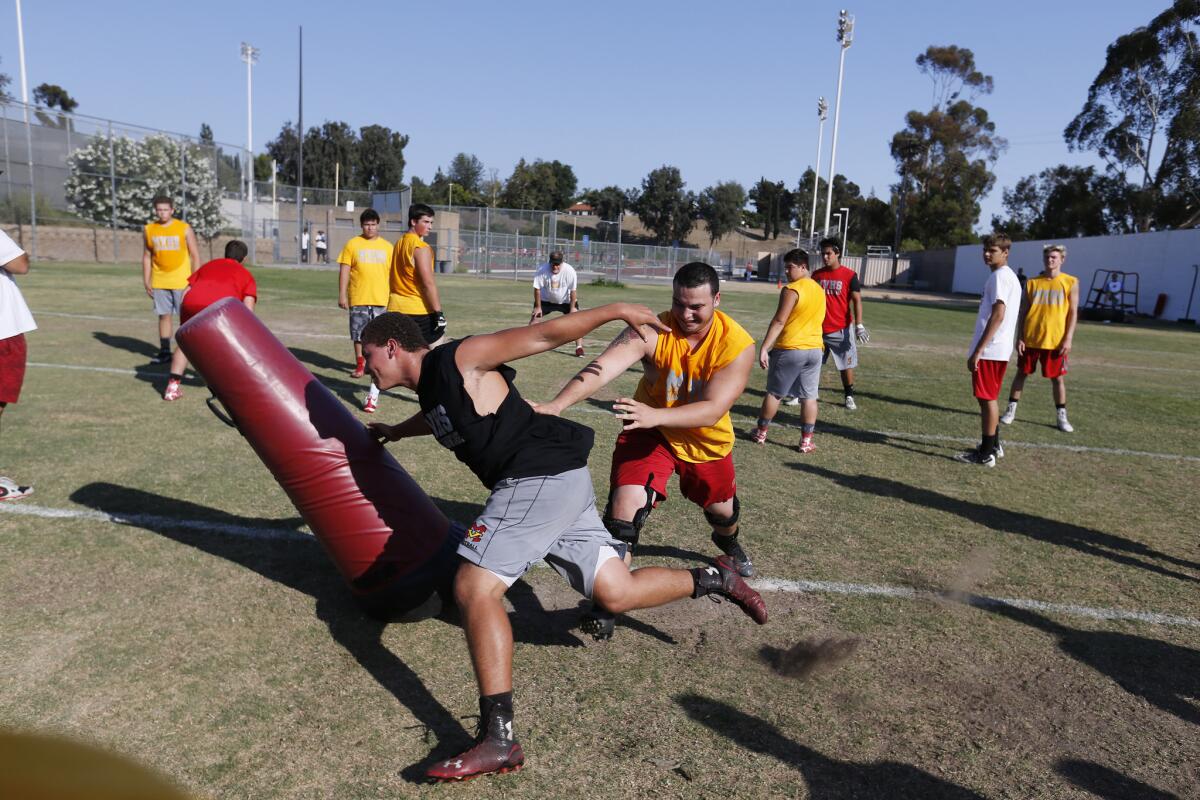 High School football players participate in a drill as the Oregon and Mission Viejo High School coaching staffs look on during a satellite camp.