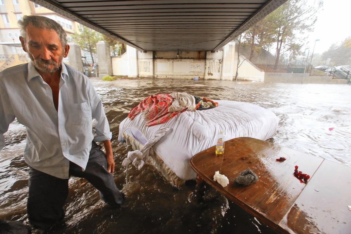 The bed of Felipe Flores Lopez, 59, floats away as he loses his homeless encampment when rainwater floods a section of Avenue 26 under the Cypress Park/Lincoln Heights Gold Line Station in Lincoln Heights.