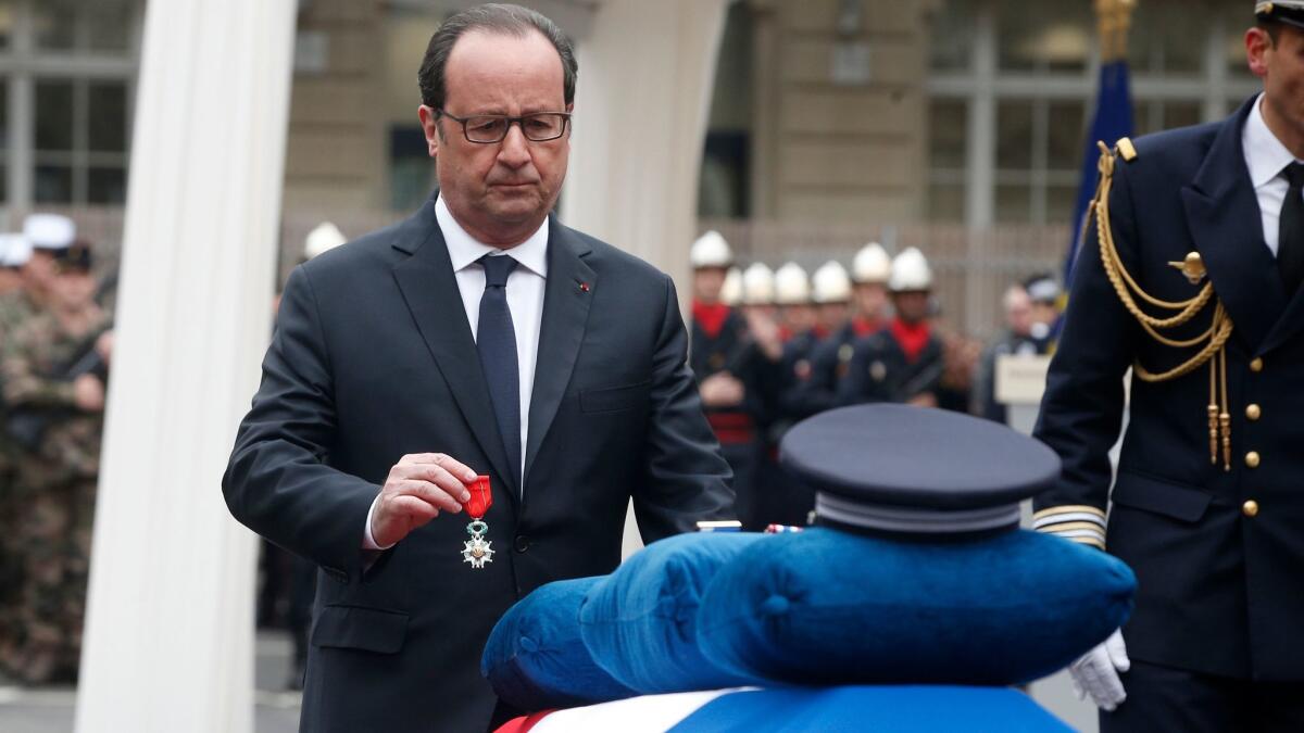 French President Francois Hollande puts a medal on the casket of slain police officer Xavier Jugele at a ceremony in Paris on Tuesday.