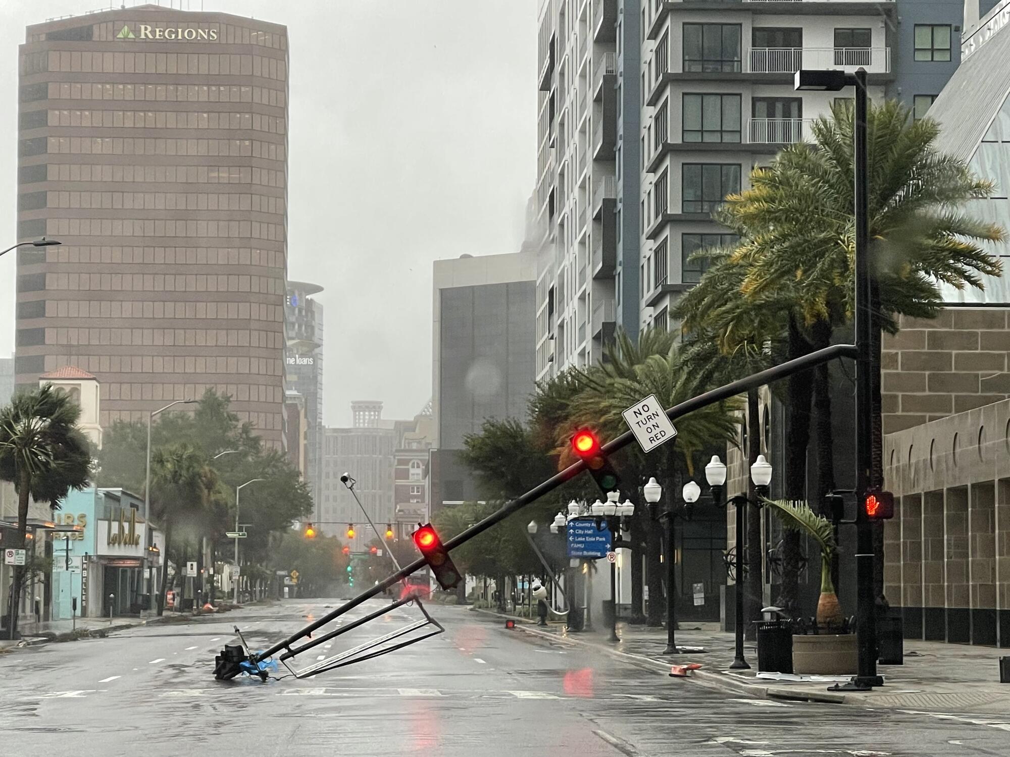 A stoplight pole blown down by Hurricane Ian winds, rests on Orange Avenue in Downtown Orlando, Fla.