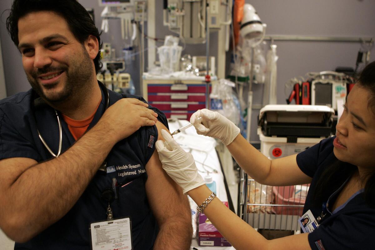 Nurse Janet Li–Tall administers a flu shot to emergency room nurse Romeo Spina in a trauma room at Ronald Reagan UCLA Medical Center. More cases of flu are expected in coming weeks.