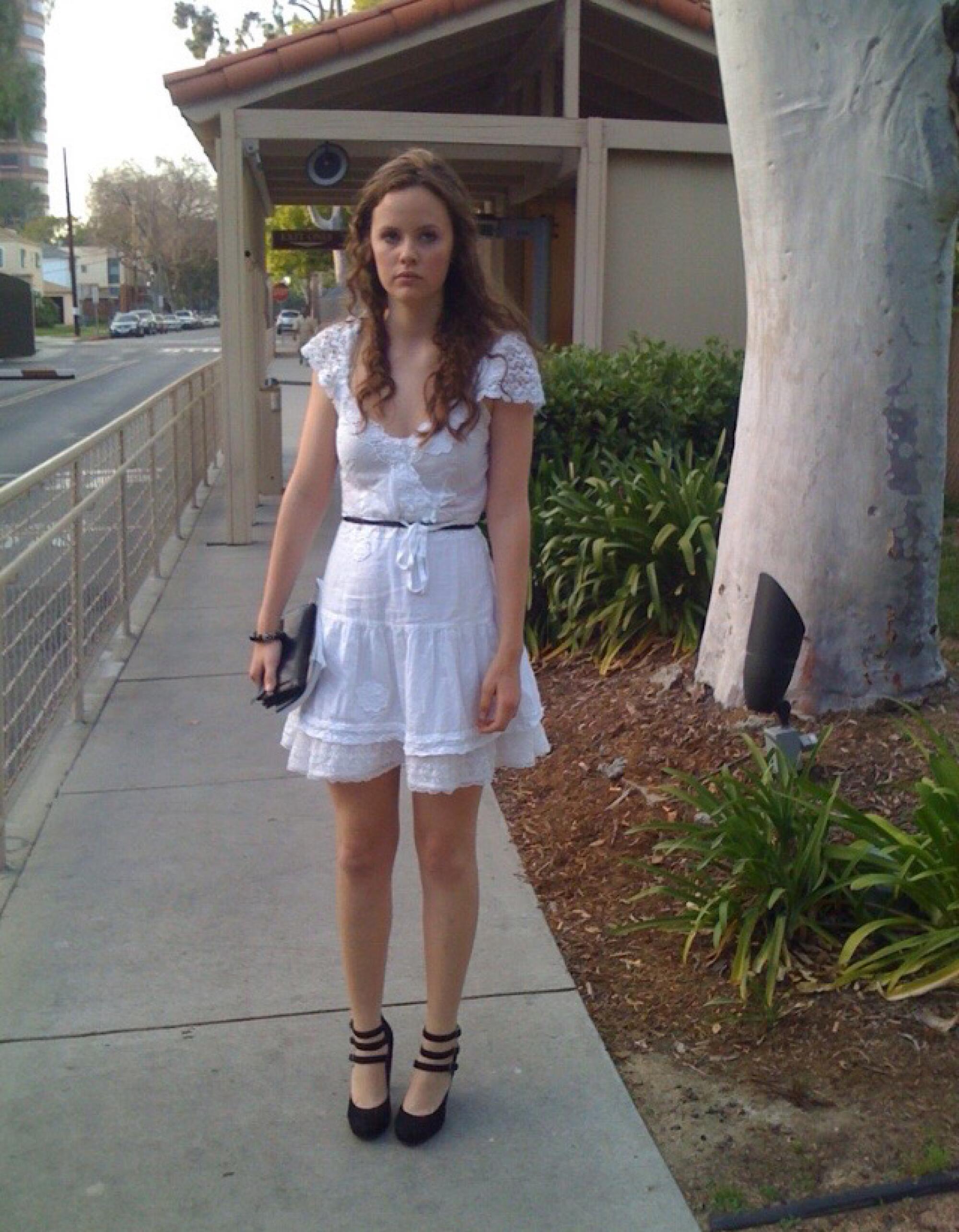 Sarah Ramos in a short white dress and high heels.