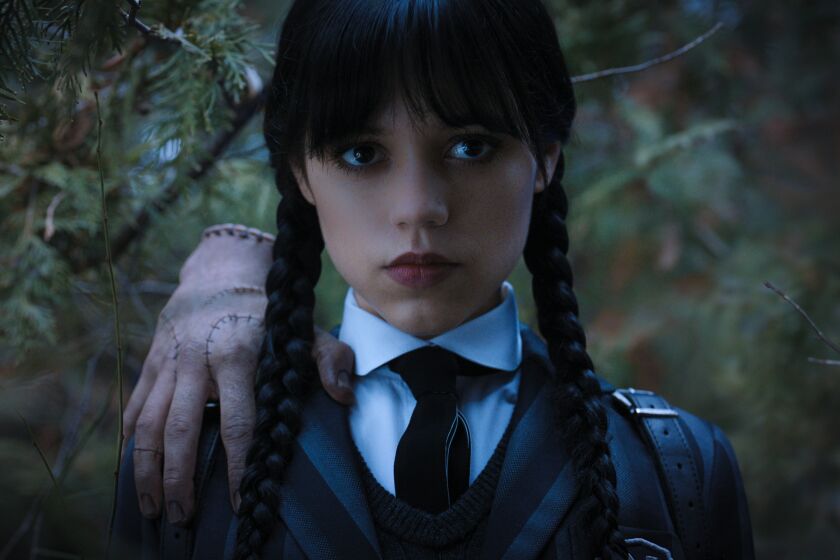A woman with long, dark pigtail braids wearing a uniform and tie. A floating hand is perched on her shoulder in the woods
