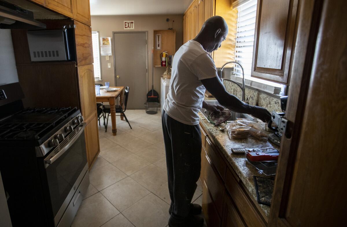 Sam Blake cleans up in the kitchen of the Blake Home, a board-and-care facility in Sylmar.