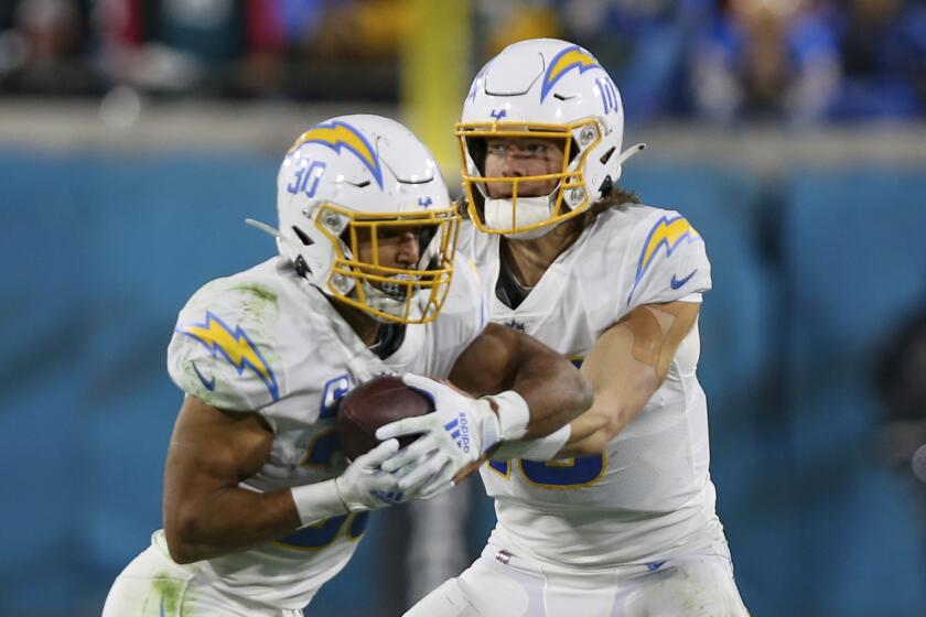 Los Angeles Chargers quarterback Justin Herbert (10) hands off the ball to running back Austin Ekeler (30) during an NFL wild-card football game against the Jacksonville Jaguars, Saturday, Jan. 14, 2023, in Jacksonville, Fla. The Jaguars defeated the Chargers 31-30. (AP Photo/Gary McCullough)