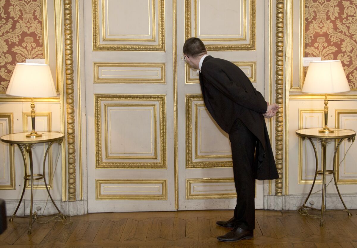 FILE - A usher looks through the key hole at the French foreign ministry in Paris, Friday March 4, 2016 during international ministerial discussions about Syria. Members of the French diplomatic corps, a mostly invisible force that guides the nation's conduct of international affairs, are dropping their traditional reserve to go on strike Thursday, angered by a planned reform they fear will hurt their careers and France's standing in the world. (AP Photo/Jacques Brinon, File)