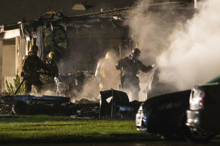 Firefighters battle heavy smoke after a plane crashed into houses on Rhonda Road in Riverside. Three people were killed.