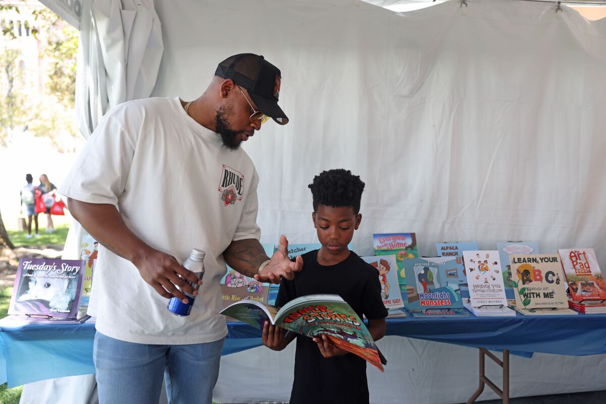 Richard Stokes and his son Karter Stokes, 8, in a booth at the Los Angeles Times Book Festival.