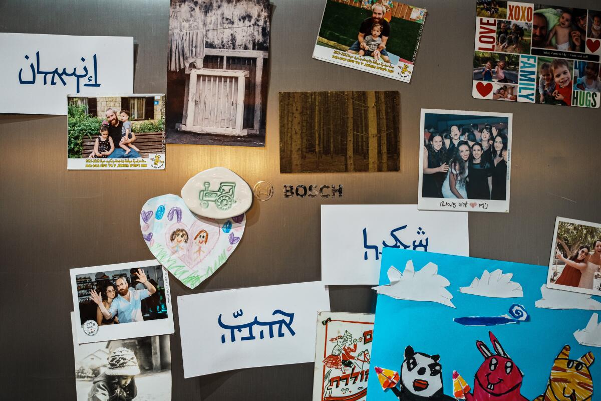 Photographs and cards, including a few bearing blue script, on a refrigerator door.