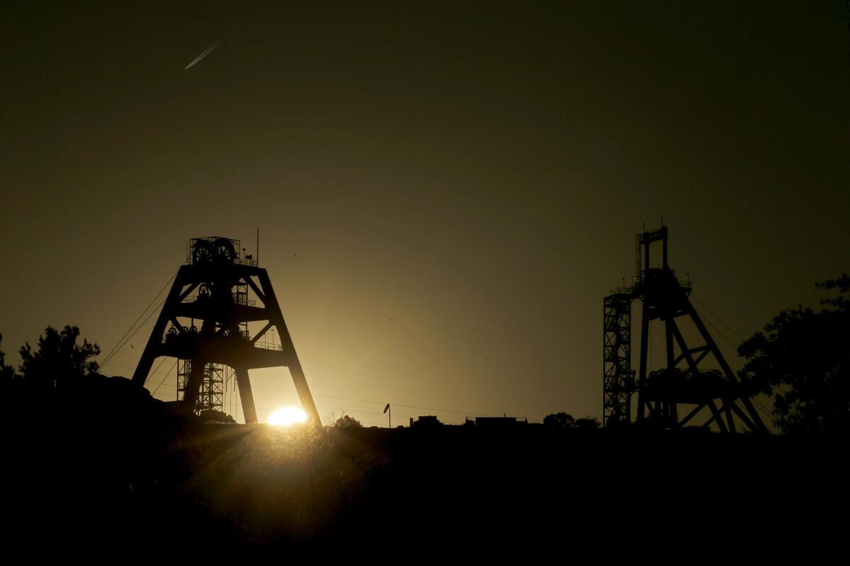 Mine shaft infrastructure is silhouetted against the setting sun 