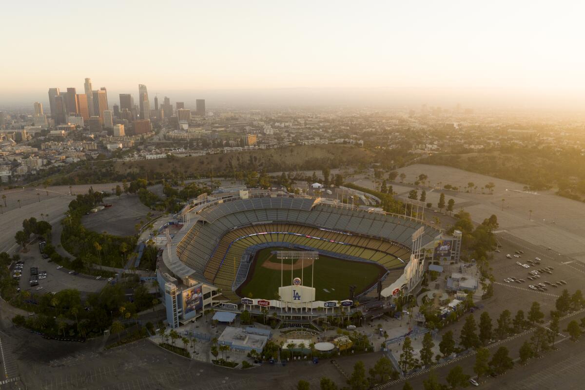 A baseball stadium is seen from above. In the background is a city skyline amid smog.