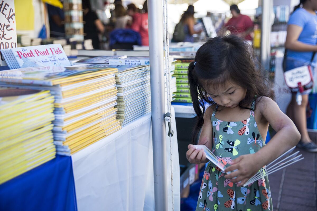 Maya Chen, 4, looks at a book during the first day of the annual Los Angeles Times Festival of Books.
