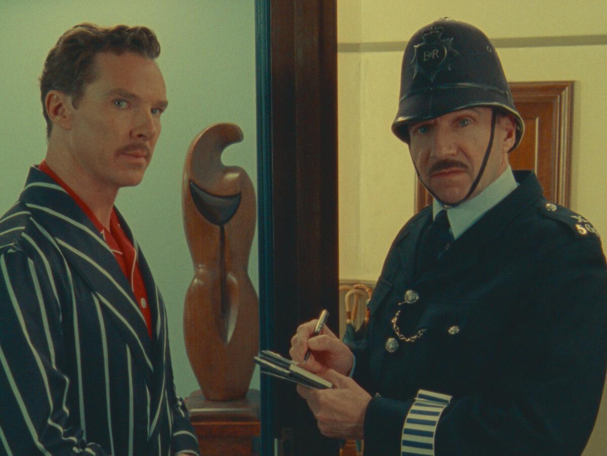 A man stands at his front door speaking to a police constable in a scene from the movie "The Wonderful Story of Henry Sugar."