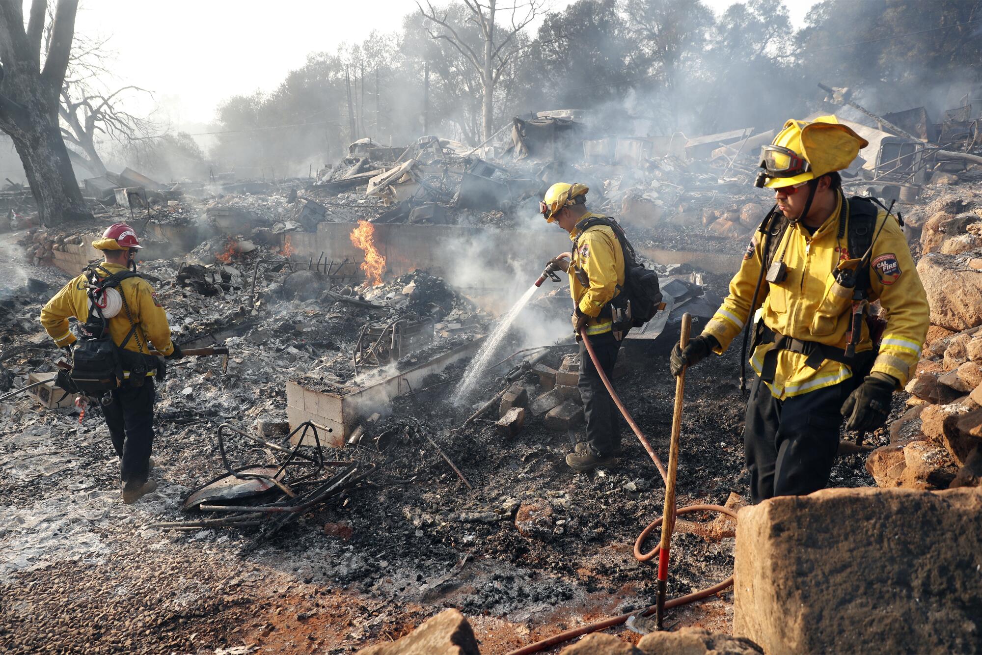 CalFire firefighters extinguish hot spots in the at Creekside Mobile Home Park during Cache Fire in Clearlake