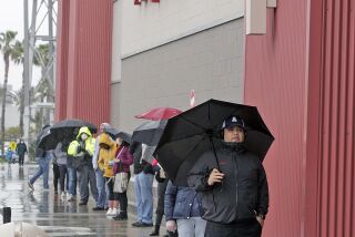 Socially distant Target shoppers wait in the rain at Target at the Empire Center in Burbank on Thursday, April 9, 2020. The Target Clinic care provided by Kaiser Permanente is temporarily closed due to COVID-19.