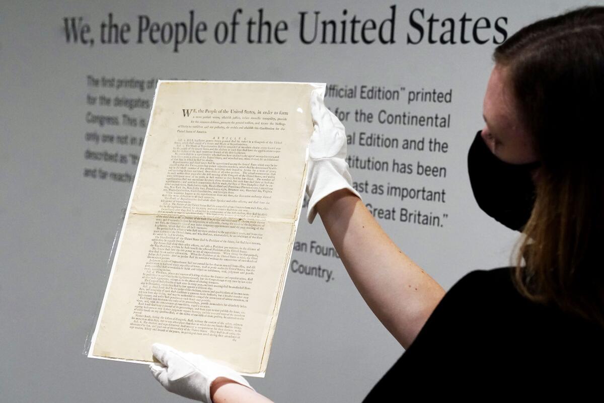 A 1787 copy of the U.S. Constitution is held up for display at Sotheby's in New York in 2021. 