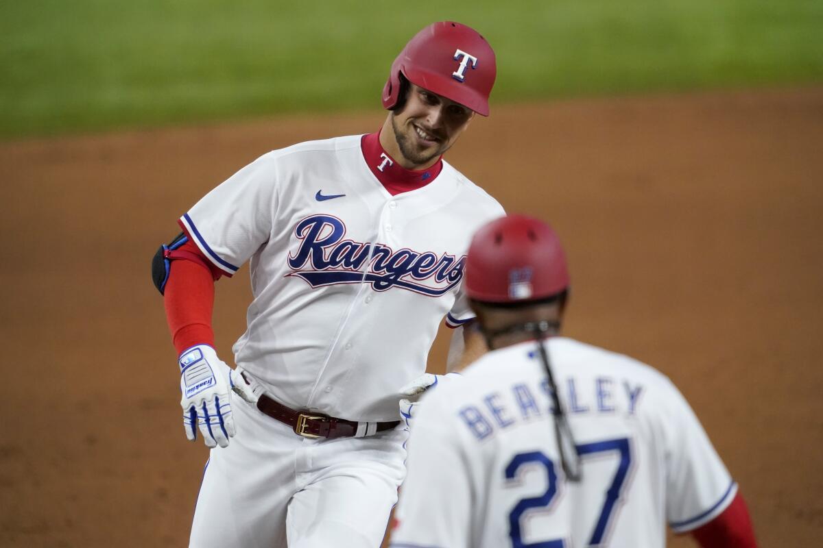 Texas Rangers' Nate Lowe, left, rounds third and is congratulated by third base coach Tony Beasley (27) after hitting a two-run home run against the Toronto Blue Jays during the first inning of a baseball game in Arlington, Texas, Tuesday, April 6, 2021. (AP Photo/Tony Gutierrez)