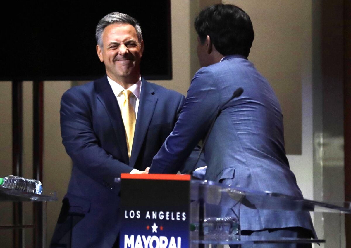 City Councilmen Joe Buscaino, left, and Kevin de León greet each other at the start of the debate.