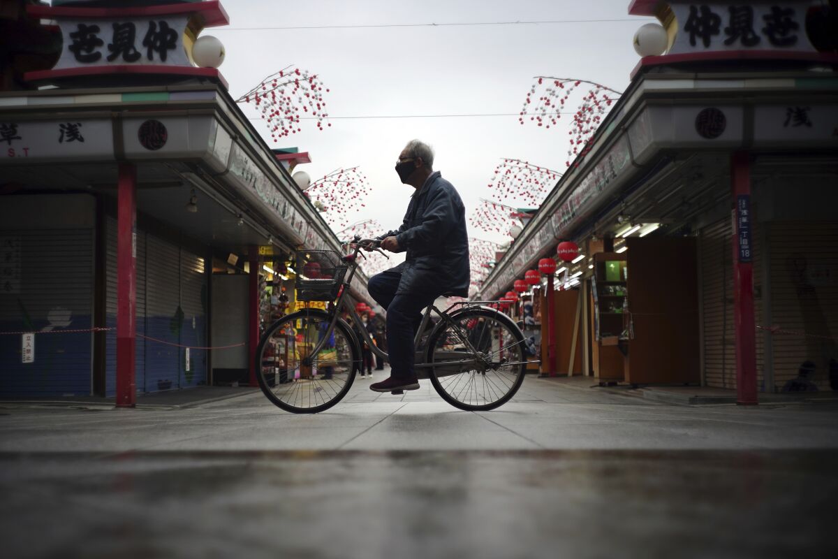 FILE - A lone bicyclist cycles through an empty shopping arcade at the Asakusa district in Tokyo Tuesday, Jan. 12, 2021. Surging prices are haunting consumers and confounding economic planners in the U.S. and other countries, but not in Japan, where sparking inflation has proven an elusive goal. (AP Photo/Eugene Hoshiko, File)