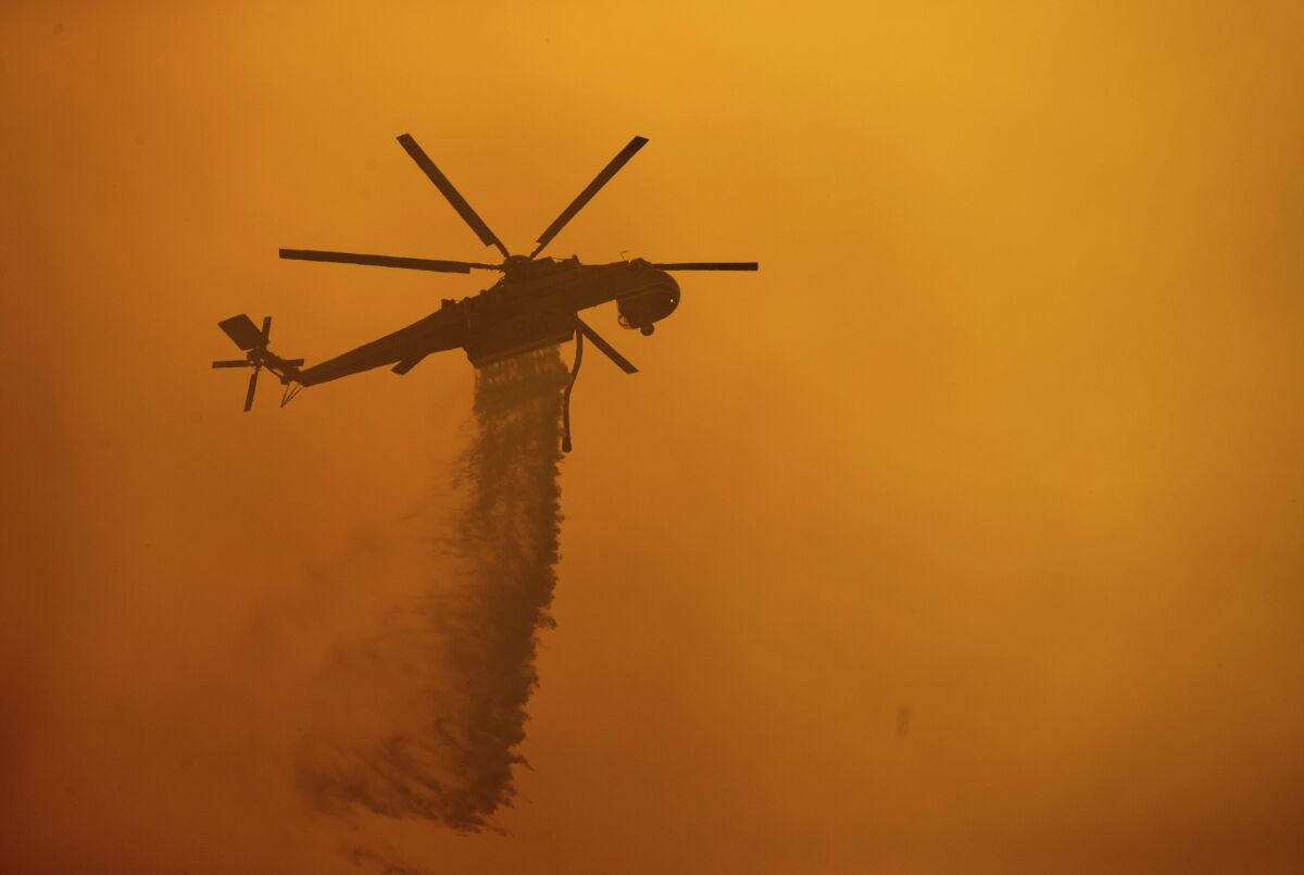 A helicopter drops water on the Fawn fire.