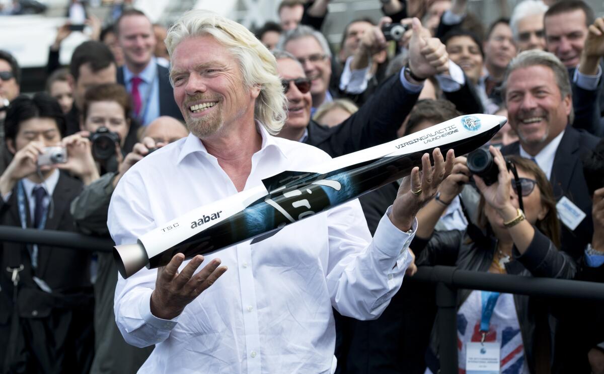 Virgin Galactic founder Richard Branson shows a model of LauncherOne to the crowd at the Farnborough International Airshow in Hampshire, England, on July 11, 2012. LauncherOne is designed to deliver small satellites into orbit.