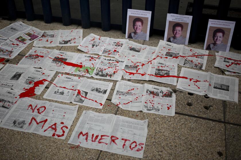 FILE - In this March 25, 2017 file photo, a message that reads in Spanish: "No More Deaths" is written in red paint on newspapers placed in front of photos of murderd Mexican journalist Miroslava Breach, at the headquarters of Mexico's General Attorney's Office in Mexico City. Mexico topped the list of journalists killed in retaliation for their work in 2020, followed by Afghanistan and the Philippines, according to a report by the New York-based Committee to Protect Journalists. (AP Photo/Eduardo Verdugo, File)