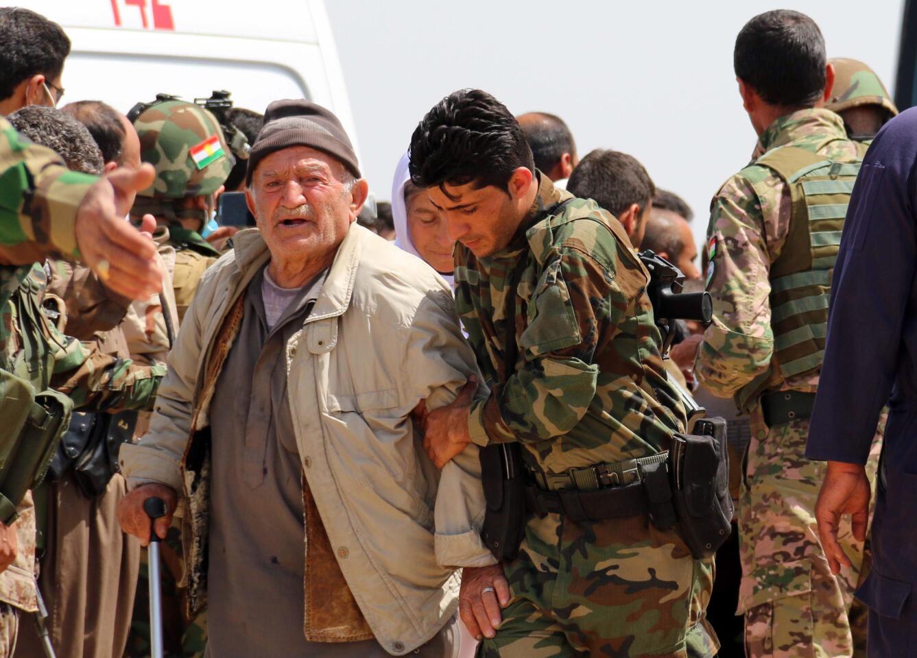 Kurdish Peshmerga forces help people from Iraq's Yazidi minority in the village of al-Humeira on April 8, 2015 after the Islamic State group freed more than 200 Yazidis it held captive for months.