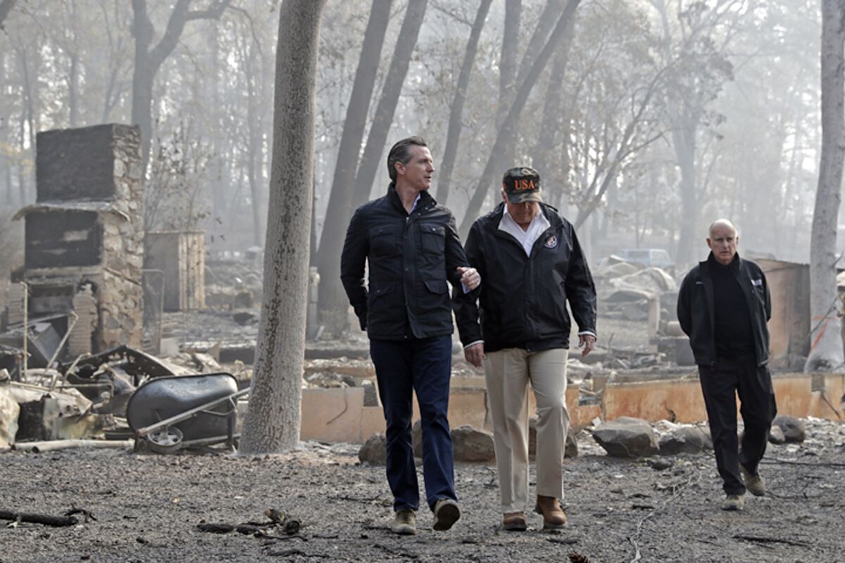 President Donald Trump talks with California Gov.-elect Gavin Newsom, left, as California Gov. Jerry Brown, walks at right during a visit to a neighborhood destroyed by the Camp wildfire in Paradise on Nov. 17, 2018.