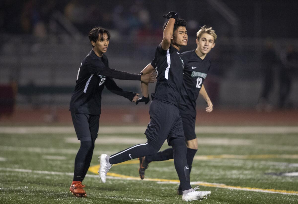Costa Mesa's Anthony Malagon, left, and Jackson Galitski, right, celebrate with Marco Castrejon after he scored a goal in the 48th minute of an Orange Coast League match against Estancia on Wednesday.