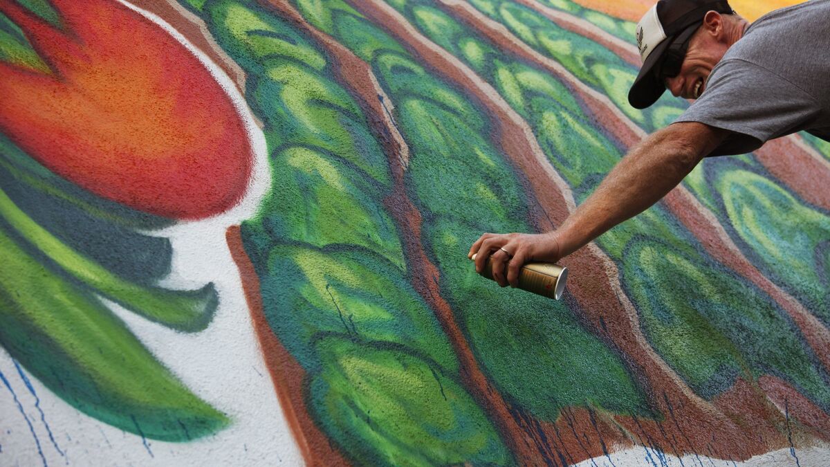 Former USC and Los Angeles Raiders star Todd Marinovich uses spray paint while working on his commissioned mural on the side of the GEM Theater in Garden Grove in 2014.
