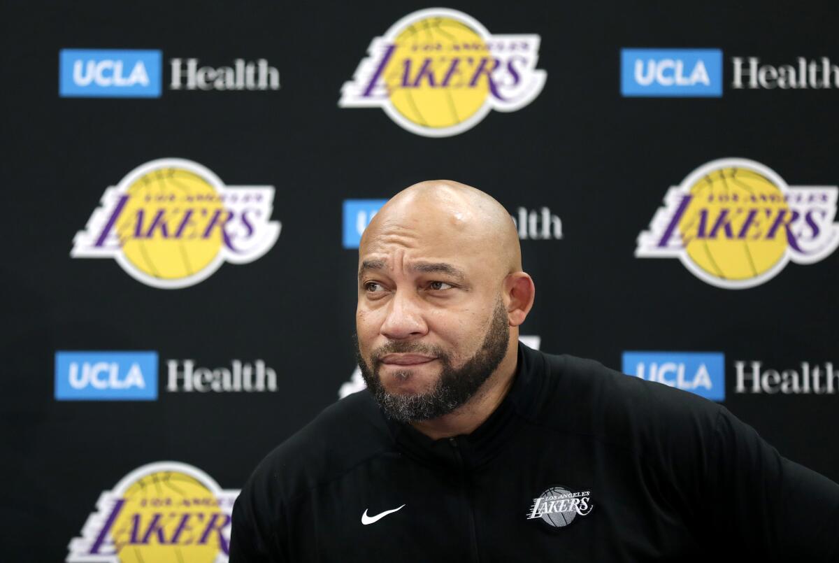 Lakers head coach Darvin Ham sits at a table listening to a reporter's question during media day.
