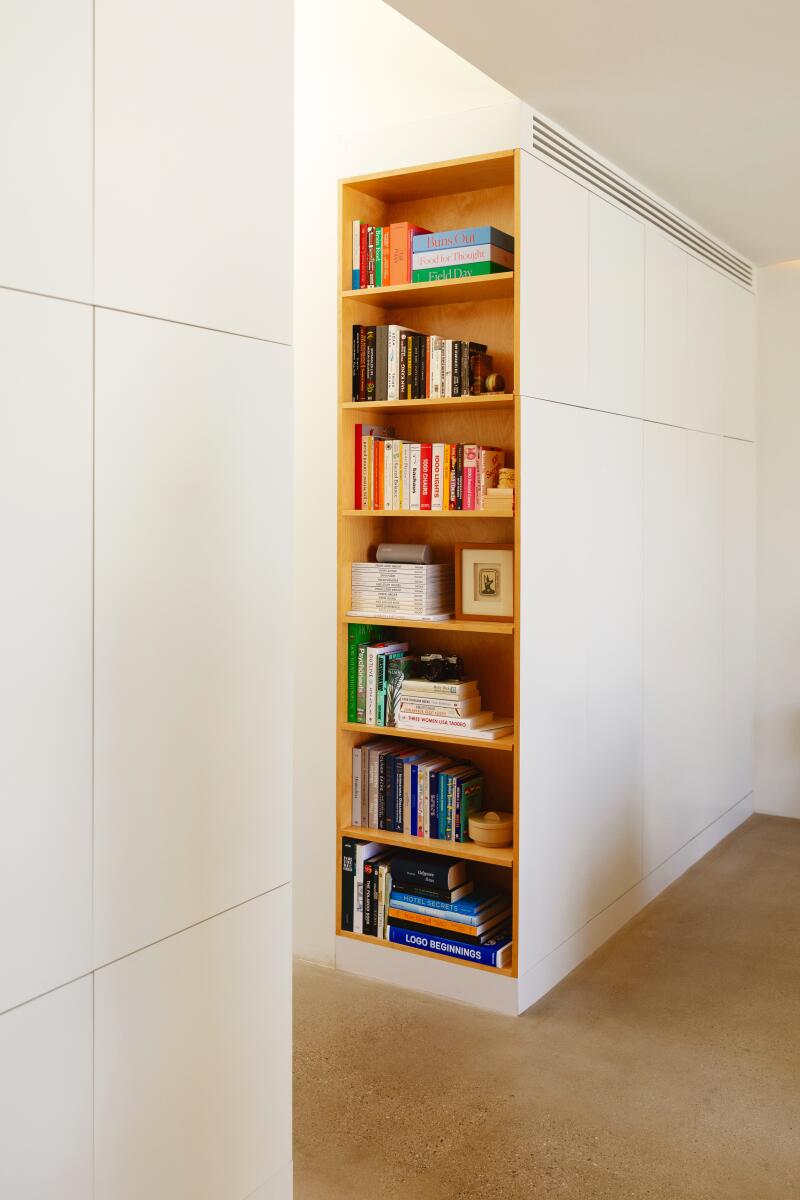 A white storage wall with wood built-in bookshelves on the end
