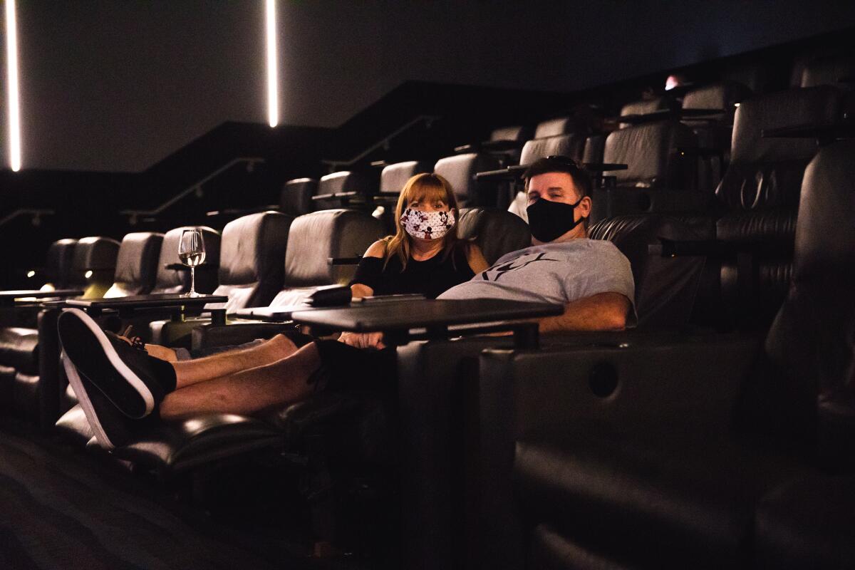 Heather and Sam Cunning pose with their masks in one of the theaters at The Lot in Liberty Station.