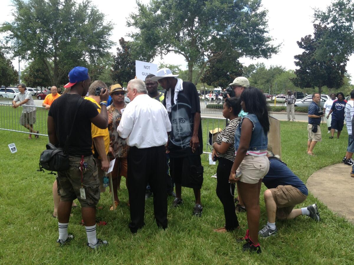 Casey Kole, center in white shirt, has watched the George Zimmerman case unfold on TV and believes he is innocent. Outside the courthouse on Saturday he talks with a group of Trayvon Martin supporters.