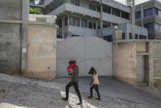 People walk past the front entrance of the Sisters of Saint-Anne residence in Port-au-Prince, Haiti, Monday, Jan. 22, 2024. The Archdiocese of Port-au-Prince is pleading for the release of six nuns from the congregation who were kidnapped last week and demanding that Haiti's government crack down on gang violence. AP Photo/Odelyn Joseph)