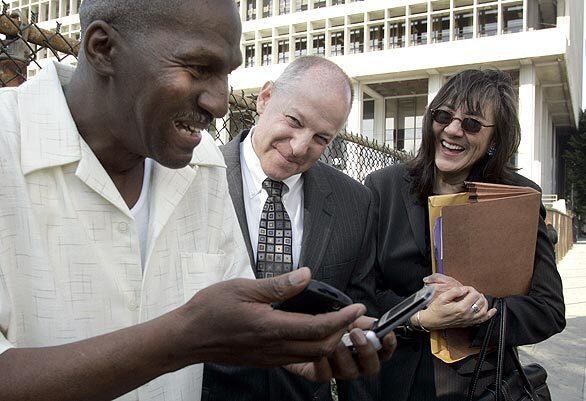 Willie Earl Green, left, marvels at a couple of cell phones with his attorneys Peter Camiel and Verna Wefald at his side.