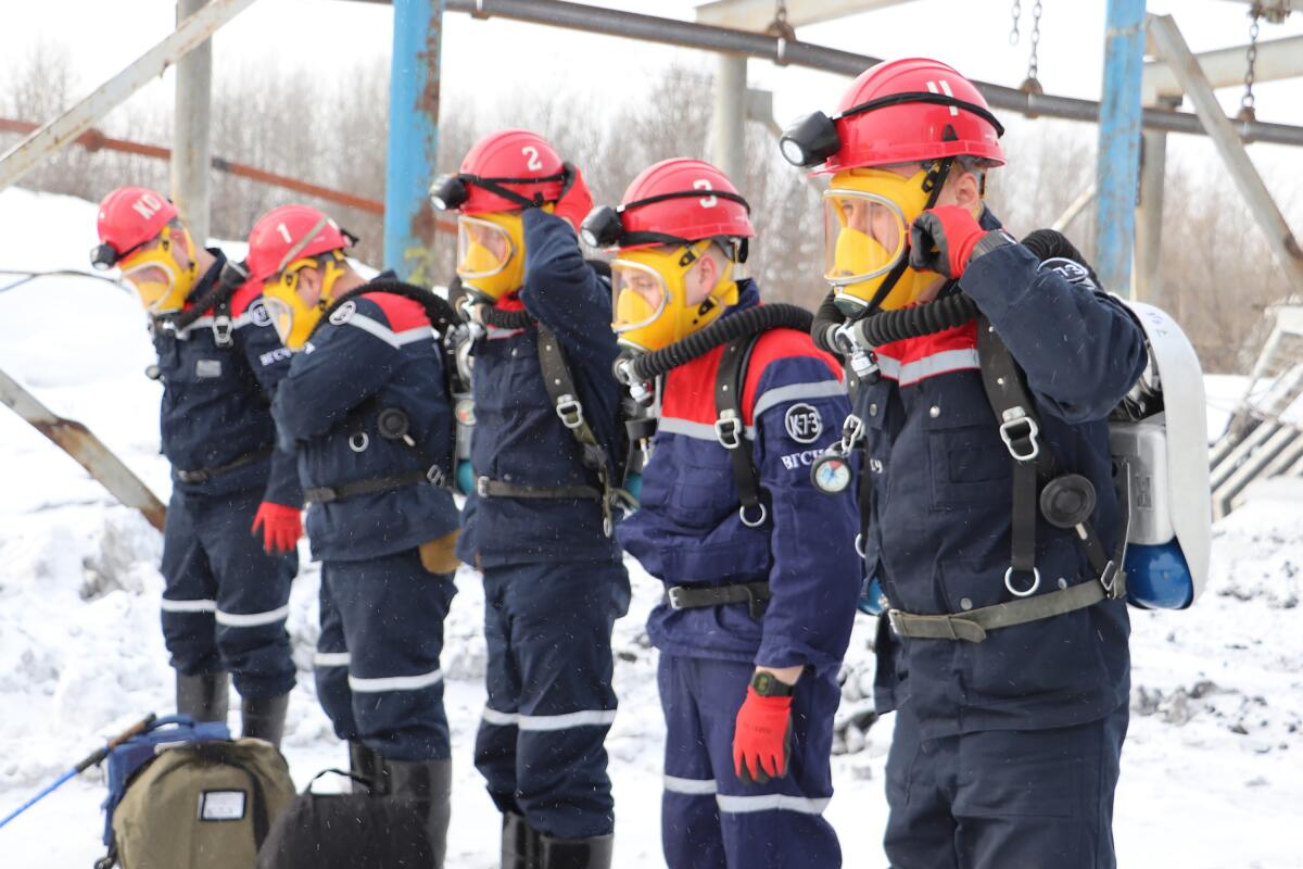 Five people dressed in emergency gear, with helmets and face masks