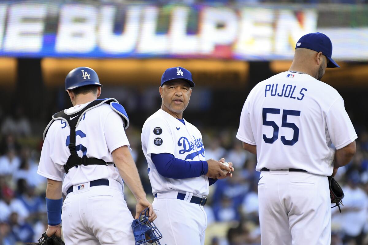 Dodgers manager Dave Roberts waits for a reliever along with catcher Will Smith and first baseman Albert Pujols.