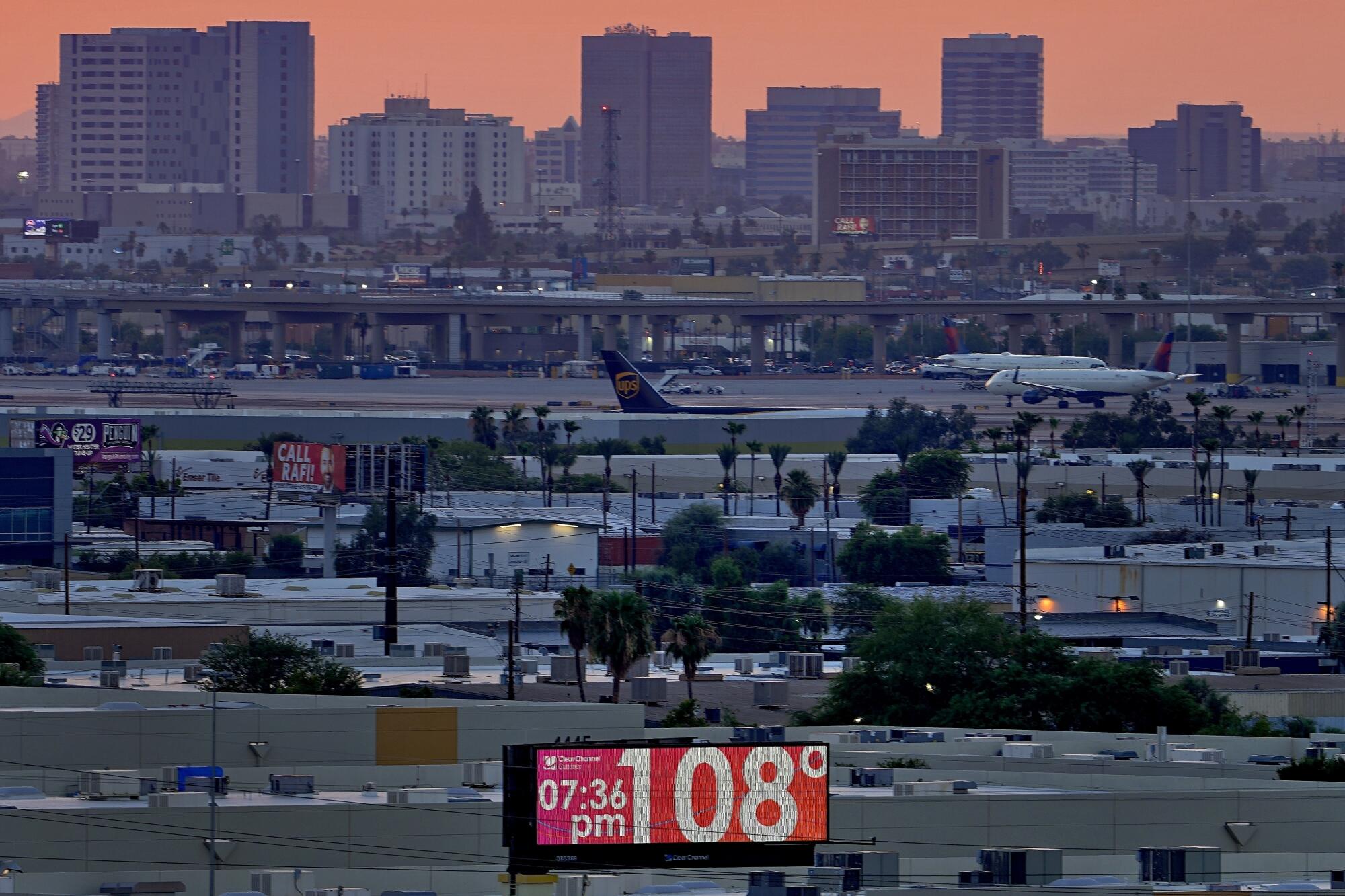 A digital sign reads 108 degrees as a city skyline rises in the background.