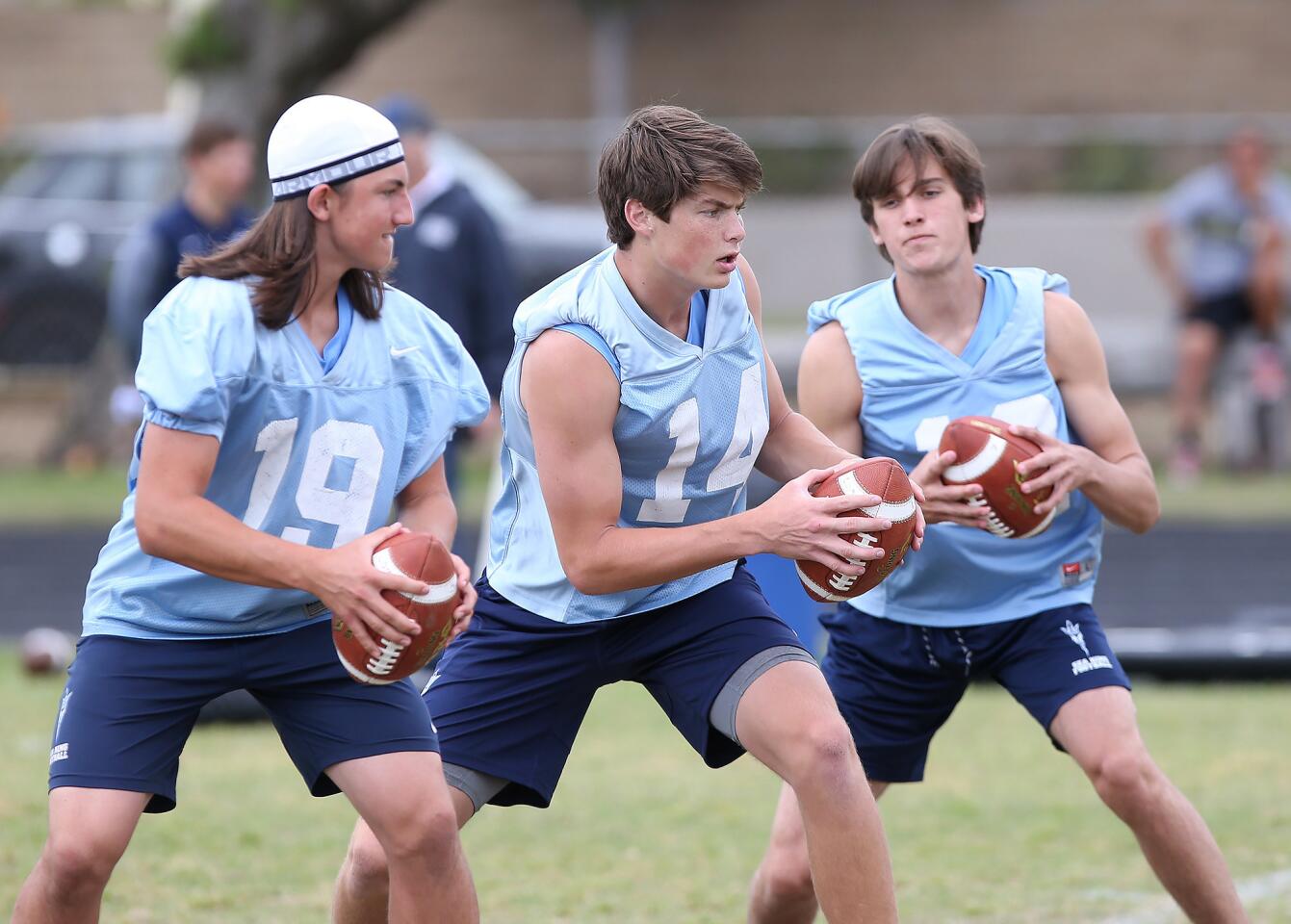 Quarterback Ethan Garbers, center, runs a play with fellow quarterbacks Dane Voorhees, left, during a spring football showcase at Corona del Mar High on Wednesday.