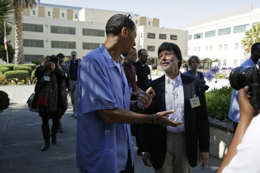 In this photo taken Wednesday, July 24, 2019, filmmaker Ken Burns walks with inmate Rahsaan Thomas at San Quentin State Prison in San Quentin, Calif. Burns visited the prison to show parts of his new documentary, Country Music, that premieres Sept. 15 on PBS. The clips shown at the prison included sections from the film about Johnny Cash's iconic performances at San Quentin, one of which inspired then-inmate Merle Haggard to pursue his own music career. (AP Photo/Eric Risberg)
