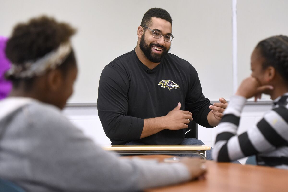 FILE - Baltimore Ravens lineman and math scholar John Urschel teaches a lesson at Dundalk High School to launch Texas Instruments' STEM Behind Cool Careers series in Baltimore, in this Tuesday, July 18, 2017, file photo. John Urschel has found that a master's degree in mathematics, his stature as an accomplished author and his pending PhD at MIT isn't necessarily enough to sell young students on the benefit of crunching numbers. What really makes him interesting to most kids is that he's a former NFL player who opted to immerse himself in math. (Steve Ruark/AP Images for Texas Instruments, File)