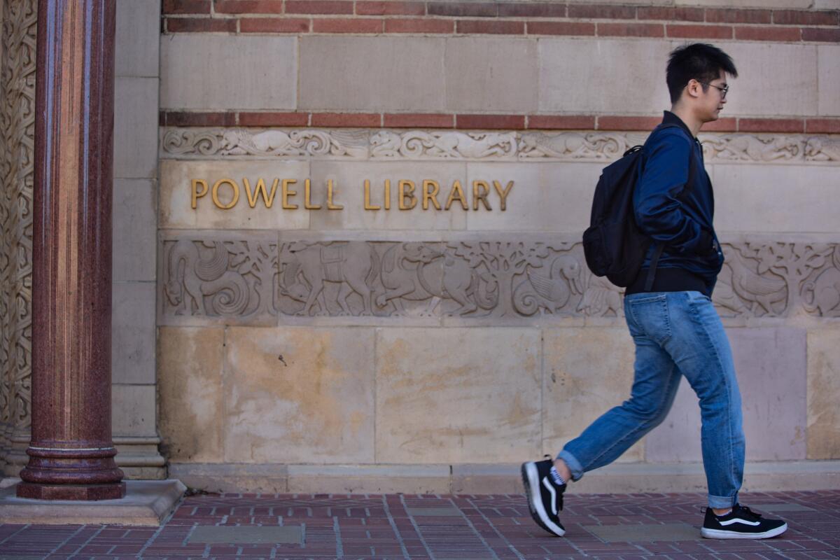 A male student walks in front of Powell Library at UCLA.