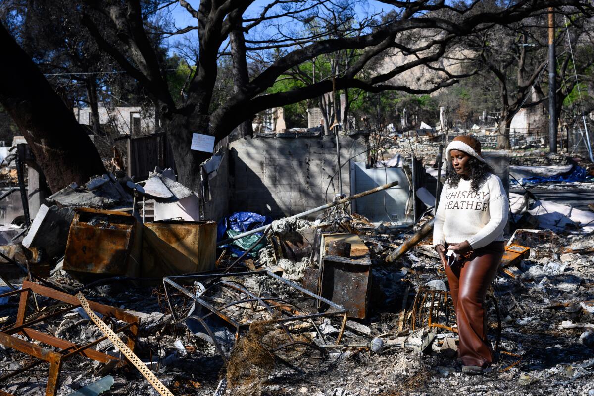 Toni Raines looks at the rubble of her family house burned by the Eaton fire.